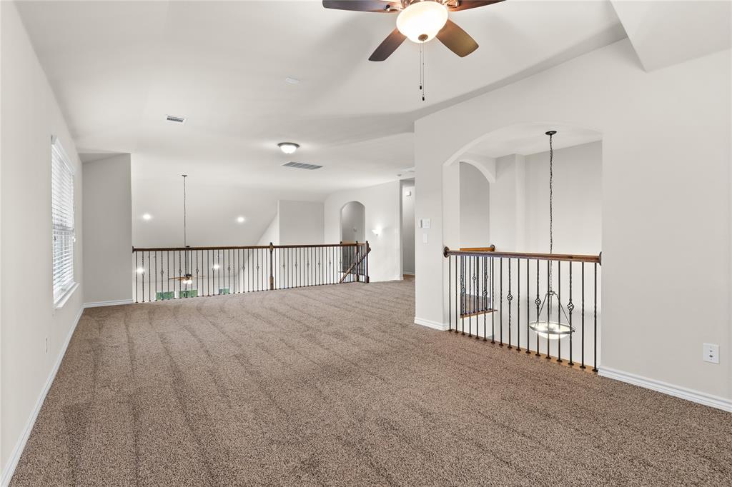 Open interior space featuring vaulted ceilings, neutral wall-to-wall carpeting, metal spindle railings, and a central ceiling fan