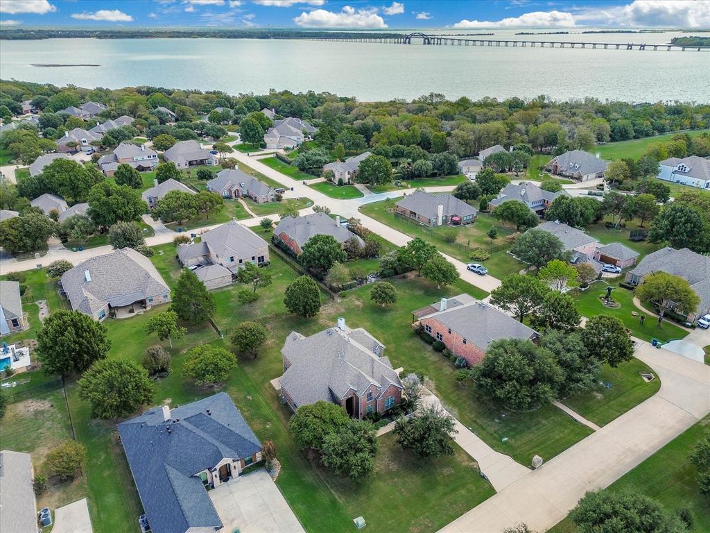 Aerial perspective featuring residential lots with established mature trees, manicured lawns, and proximity to expansive waterfront scenery