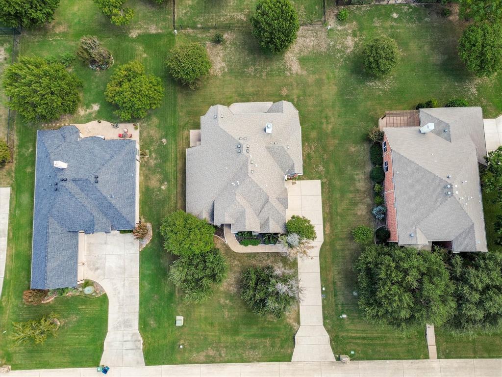 Aerial perspective featuring residential lots with concrete driveways, manicured lawns, and mature trees