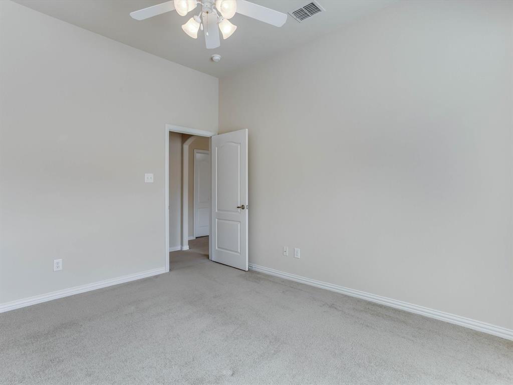 Neutral wall tones paired with neutral carpeting, high ceilings, and an overhead ceiling fan with integrated lighting