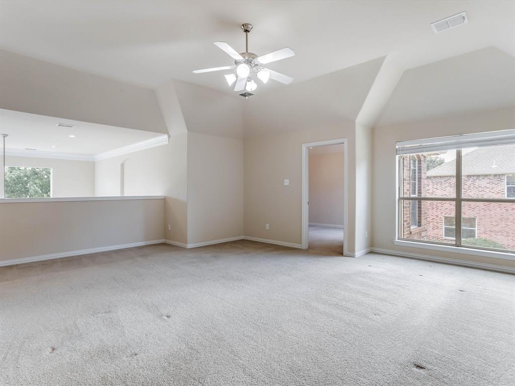 Vaulted ceiling featuring a central multi-blade ceiling fan with integrated lighting, neutral wall-to-wall carpeting, and large windows