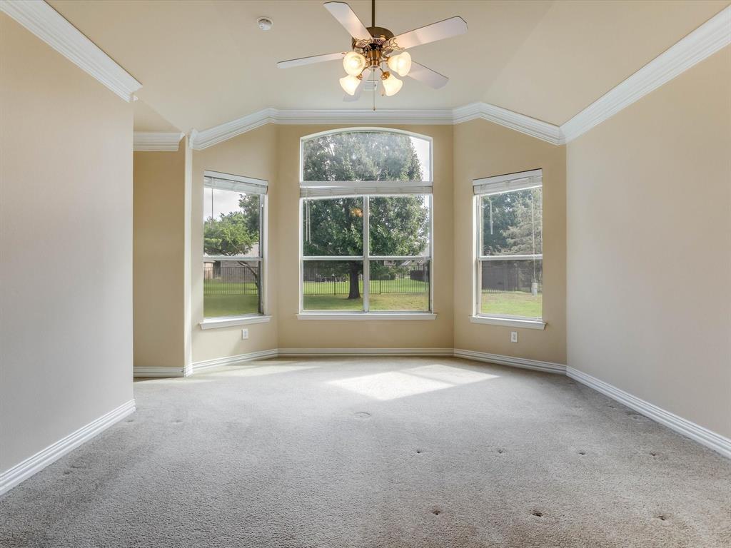 Vaulted ceilings, bay window configuration, crown molding, and a central ceiling fan fixture
