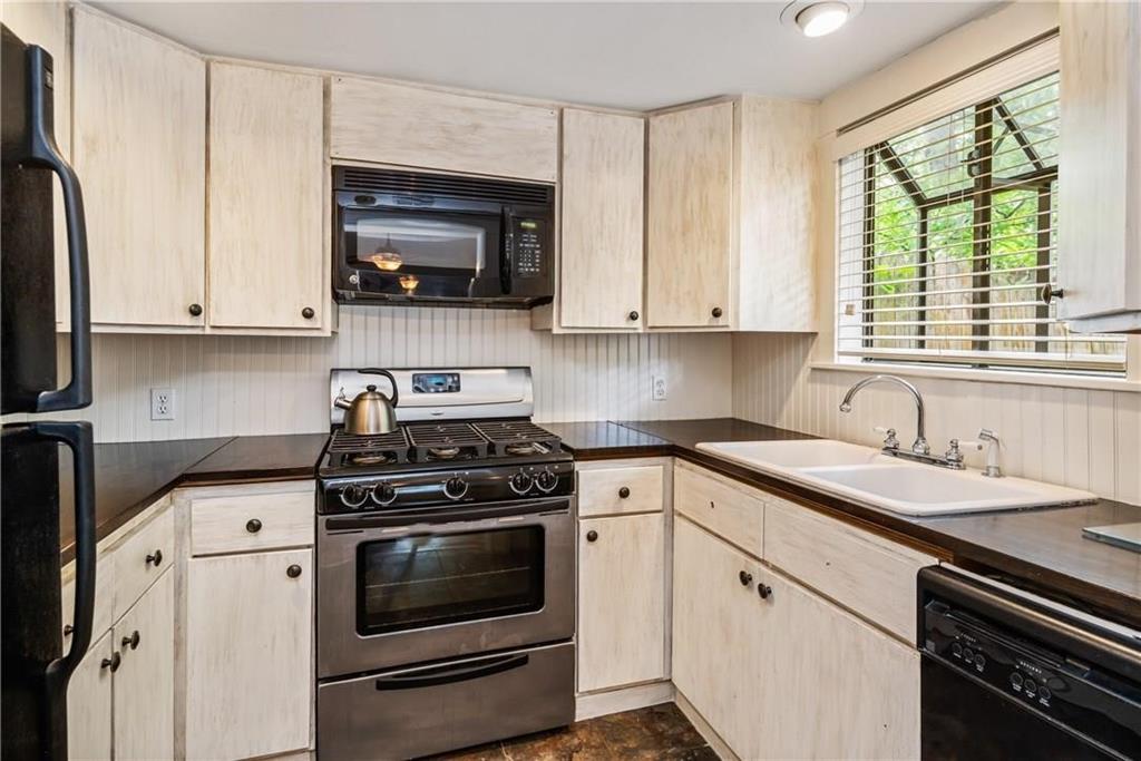 Kitchen featuring wood-finish cabinetry, stainless steel gas range, built-in microwave, dual-basin sink with gooseneck faucet, and beadboard backsplash