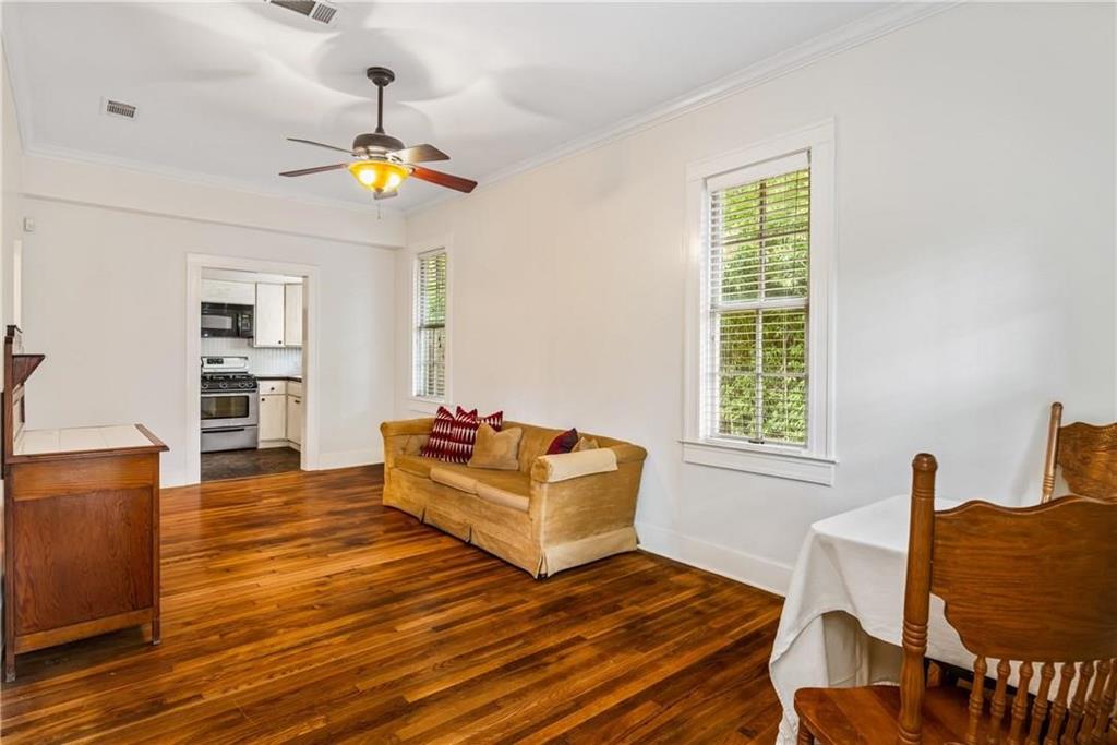 Wood-finish flooring, multi-pane windows with traditional casings, ceiling fan with integrated lighting, and crown molding
