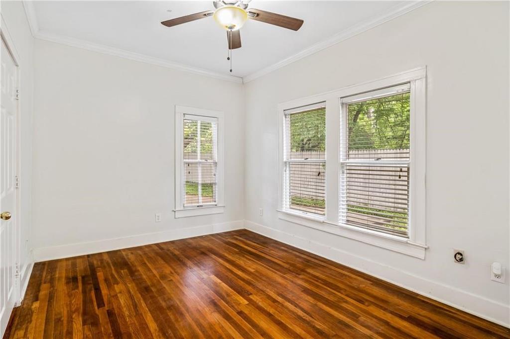 Hardwood flooring, crown molding, multi-pane windows, and a central ceiling fan with integrated lighting