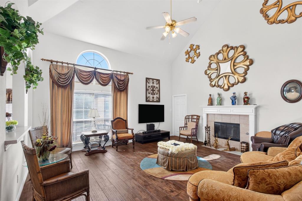 Main living room with a gas fireplace, tall windows and a high ceiling.