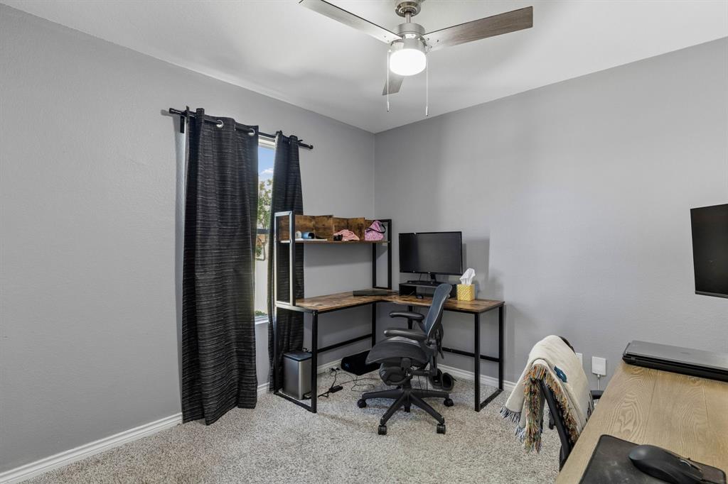The next secondary bedroom, currently used as an office, features carpet flooring, an updated ceiling fan, and a spacious walk-in closet.