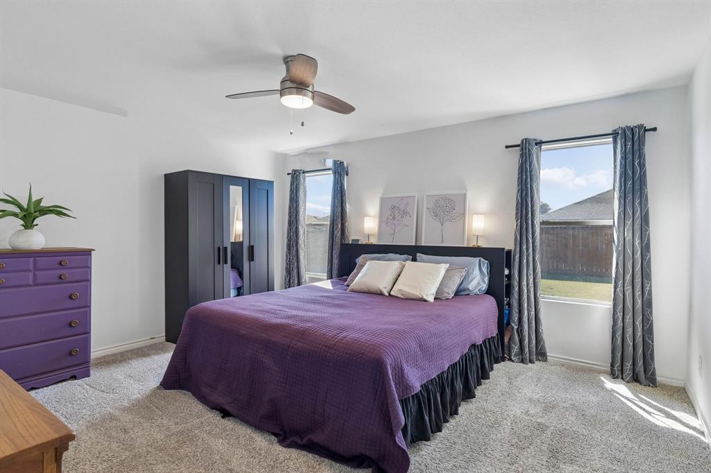 Welcome to the primary suite! Featuring an updated ceiling fan, carpet, two large windows with views to the large backyard.