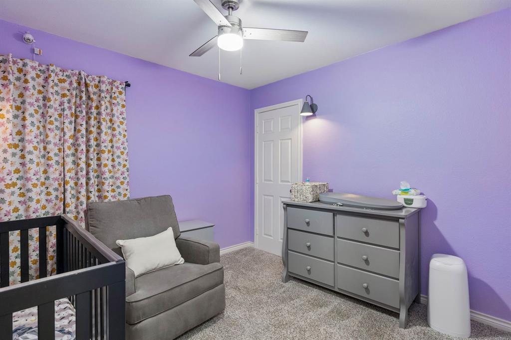 This secondary bedroom, currently used as a nursery, features carpet flooring, an updated ceiling fan, and a closet.