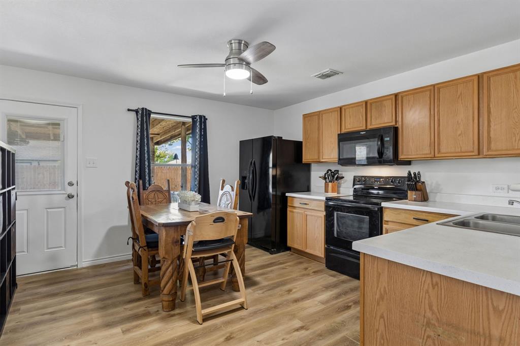 The eat-in kitchen features ample cabinet and counter space, LVP flooring, an updated ceiling fan, and black appliances. With access to the back patio and yard.