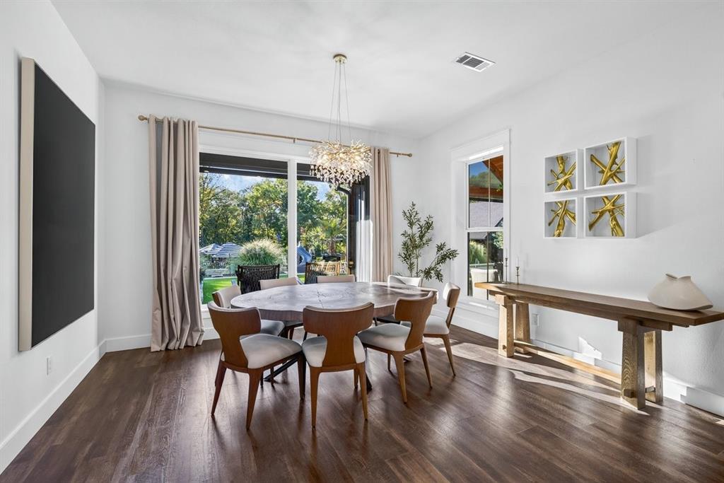 Dining area featuring beautiful wood flooring, elegant chandelier, and large picture windows overlooking the resort style backyard. Main Residence.