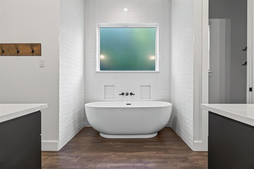 Freestanding soaking tub surrounded by beautiful tile finishes and a frosted window for natural light. Main Residence.