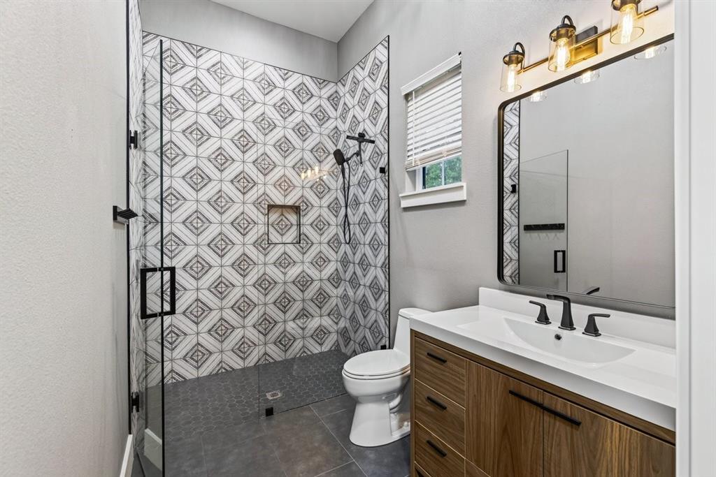 Beautifully finished bathroom with a walk-in tiled shower, frameless glass enclosure, and modern vanity in garage.