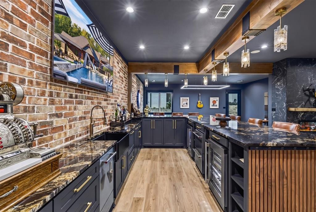 Custom-designed bar with beautiful stone countertops, brick accent wall, beverage refrigerators, and extensive cabinetry.