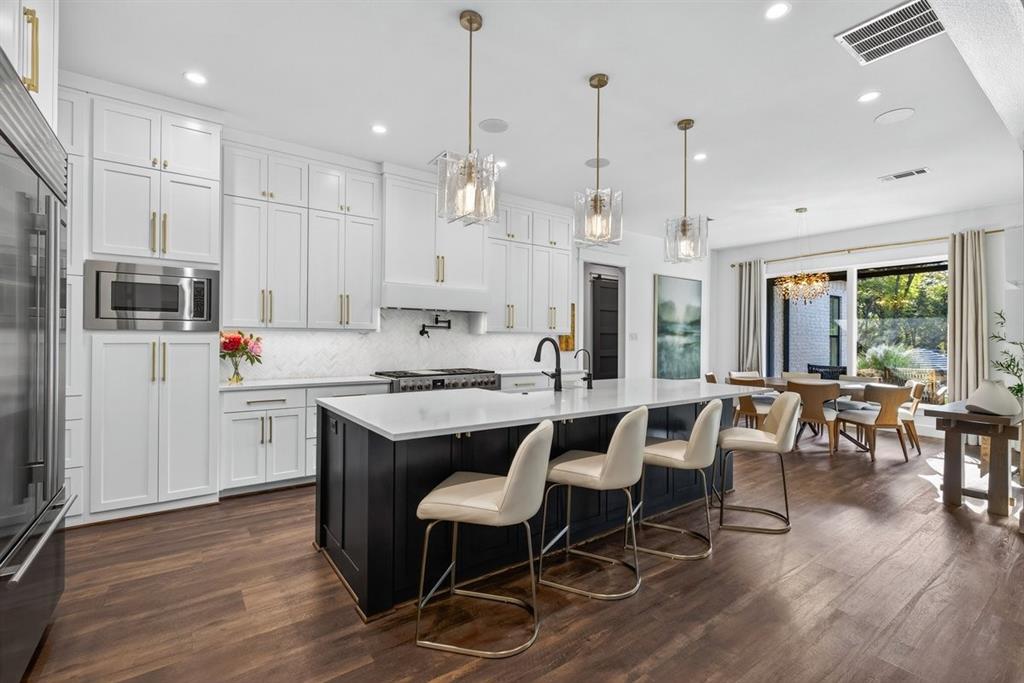 Bar seating with island storage, gas range, and elegant pendant lighting, opening to the dining area. Bar seating with island storage, gas range, and elegant pendant lighting, opening to the dining area.