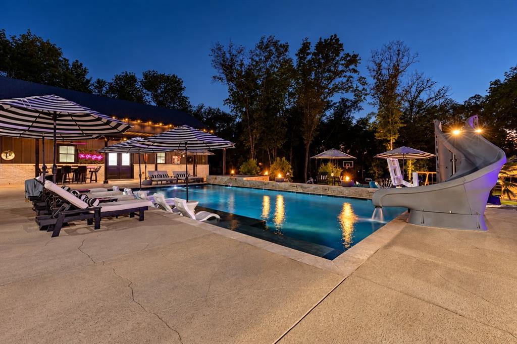 Resort-style pool with waterslide and hot tub, surrounded by multiple outdoor entertaining areas.