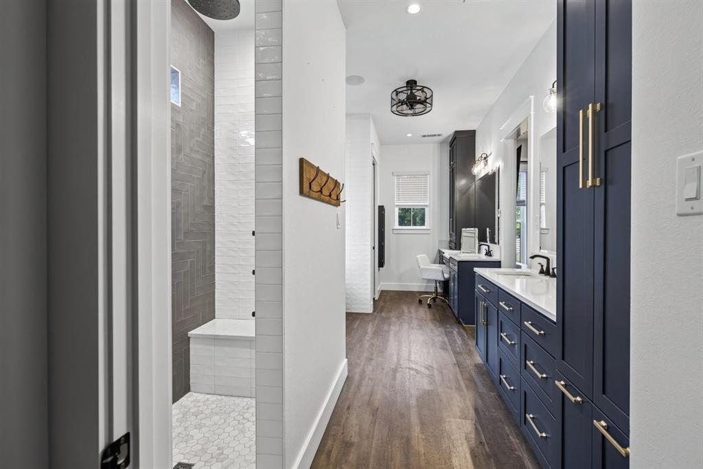 Primary bathroom featuring a walk-in shower, custom cabinetry, and an extended vanity area. Main Residence.
