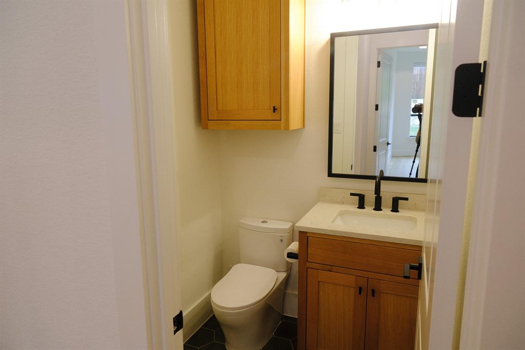 Vanity featuring wood cabinetry, a light-toned countertop with an integrated sink, and matte black fixtures