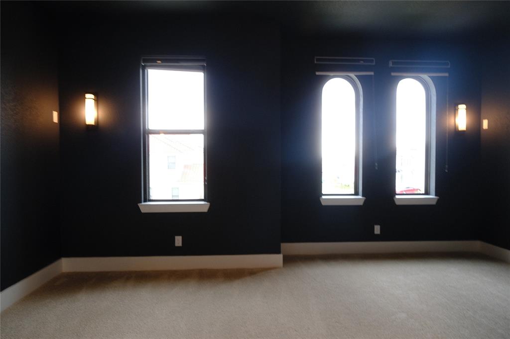 Media room featuring high-contrast wall and ceiling paint, wall-mounted light fixtures, arched windows with integrated blinds, and wall-to-wall carpeting
