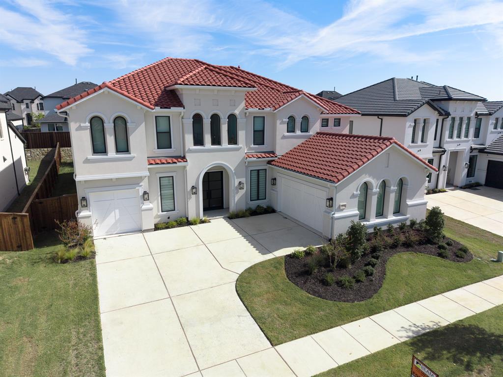 Two-story stucco exterior featuring a red tile roof, arched windows, covered entryway, and an attached three-car garage