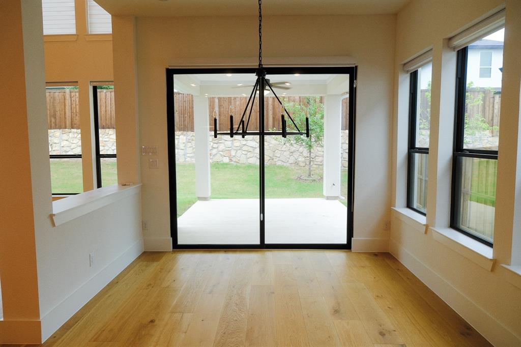 Wood-finish flooring, matte black multi-pane windows, sliding glass door, and geometric metal chandelier