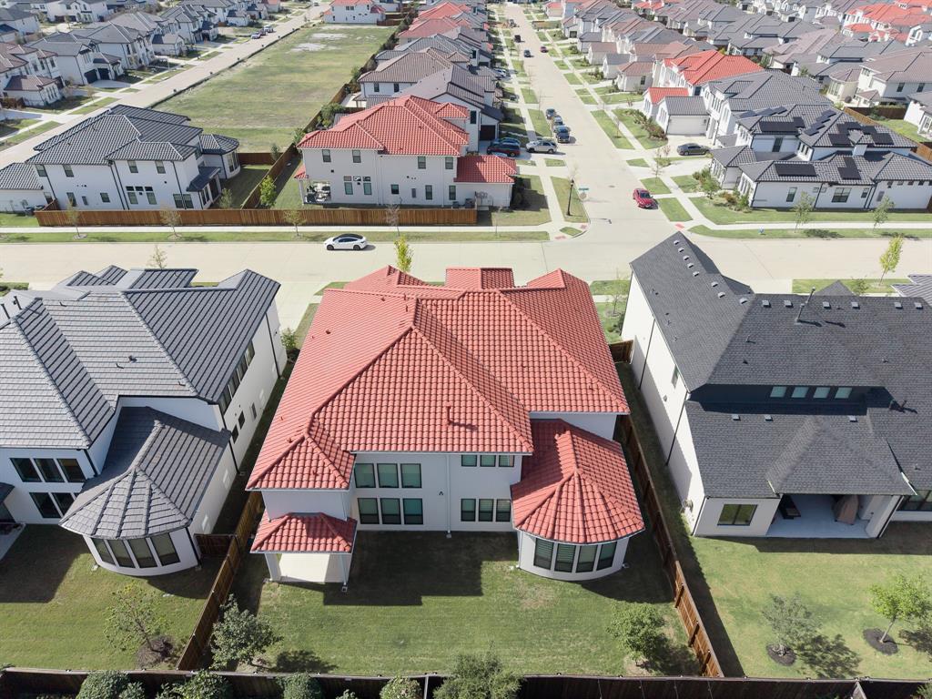 Two-story residence featuring a terracotta-style tile roof, stucco exterior, rear curved architectural bay, fenced backyard, and a covered patio