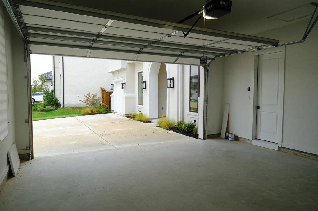 Attached two-car garage featuring a motorized sectional door, concrete flooring, and interior entry door