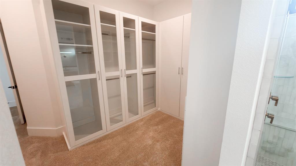 Built-in white cabinetry featuring glass-front doors, integrated shelving, and hanging rods