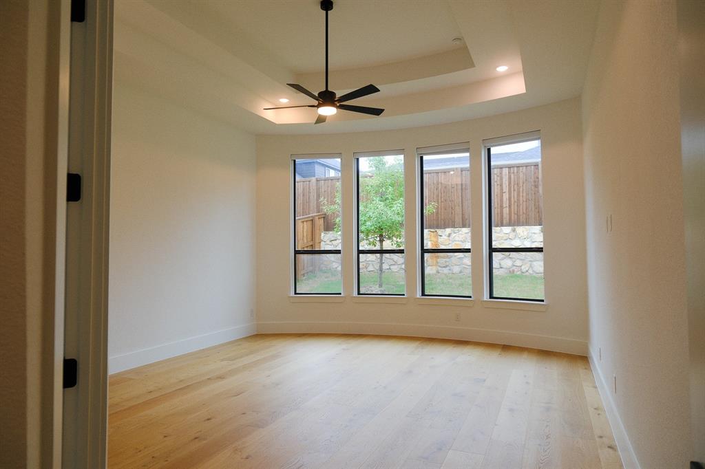 Master Bed Room featuring wood-finish flooring, a tiered tray ceiling, four floor-to-ceiling windows, and a central ceiling fan