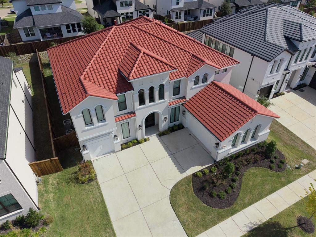 Two-story exterior featuring a red tile roof, arched windows, concrete driveway, and manicured front lawn landscaping