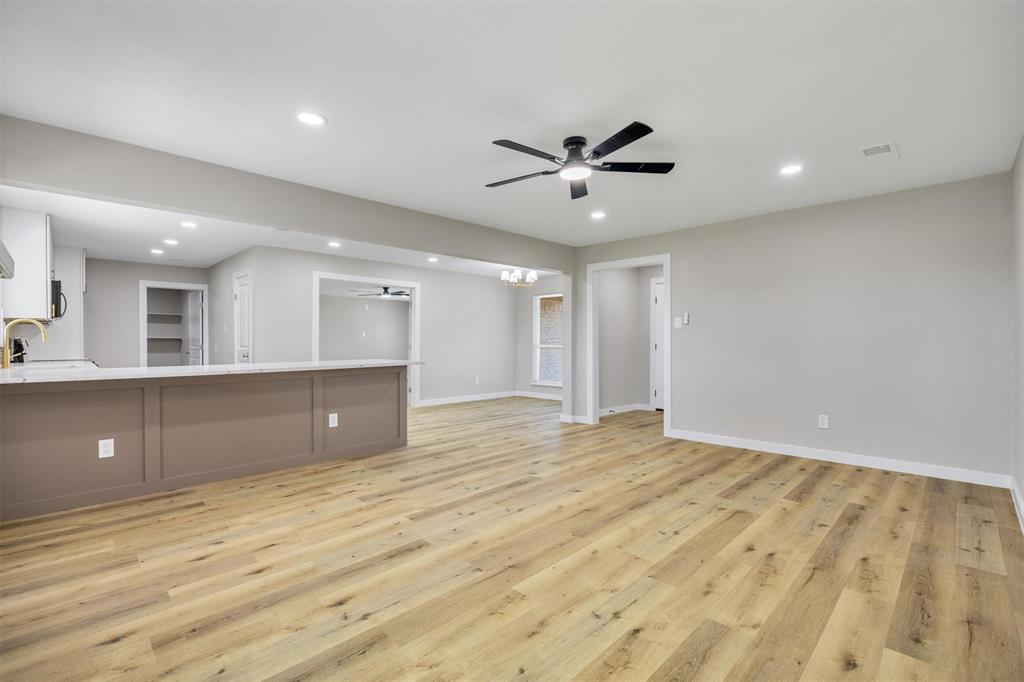 Open concept interior featuring wood-finish flooring, a kitchen peninsula with a light-colored countertop, recessed lighting, and a ceiling fan