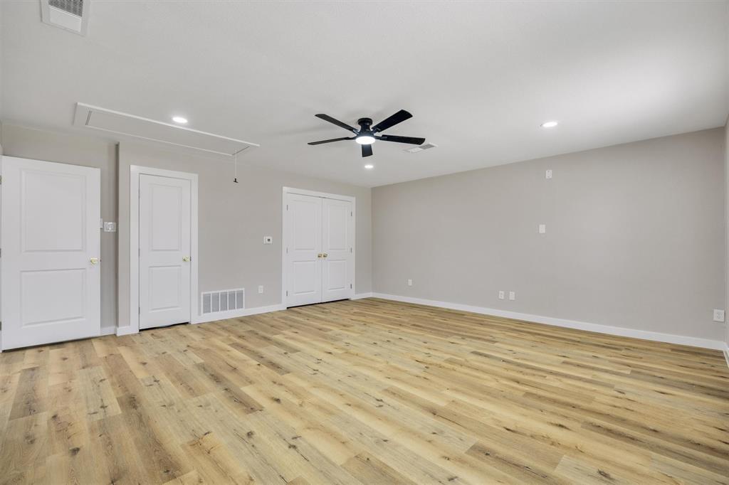 Spacious room featuring wood-finish flooring, recessed lighting, and a central ceiling fan with an integrated light fixture