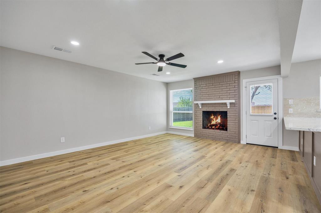 Living area featuring wood-finish flooring, brick fireplace with mantel, recessed lighting, ceiling fan, and exterior access door