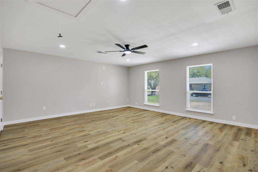 Spacious room featuring wood-finish flooring, neutral wall paint, recessed lighting, and a ceiling fan with integrated lighting