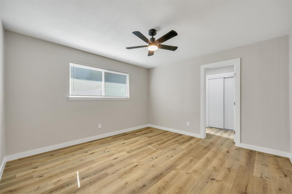 Neutral-toned walls, wood-finish flooring, ceiling-mounted light fixture with fan, and sliding closet doors