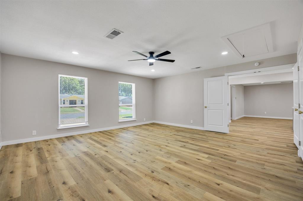 Neutral-toned interior featuring wood-finish flooring, recessed lighting, a modern ceiling fan, and double windows