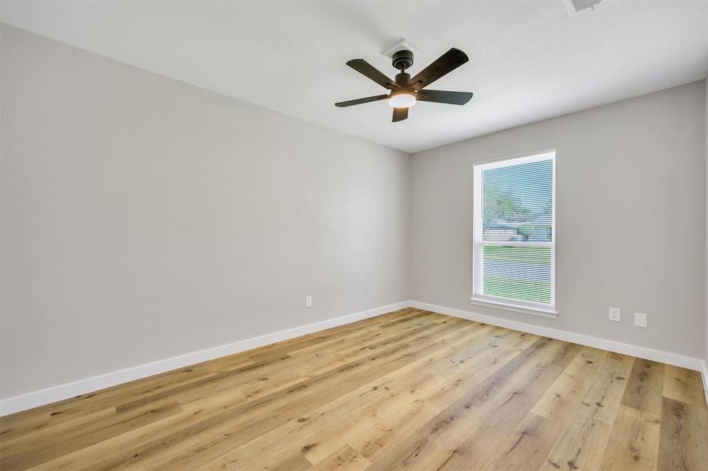Interior room featuring wood-finish flooring, a multi-blade ceiling fan with integrated lighting, and a single-pane window