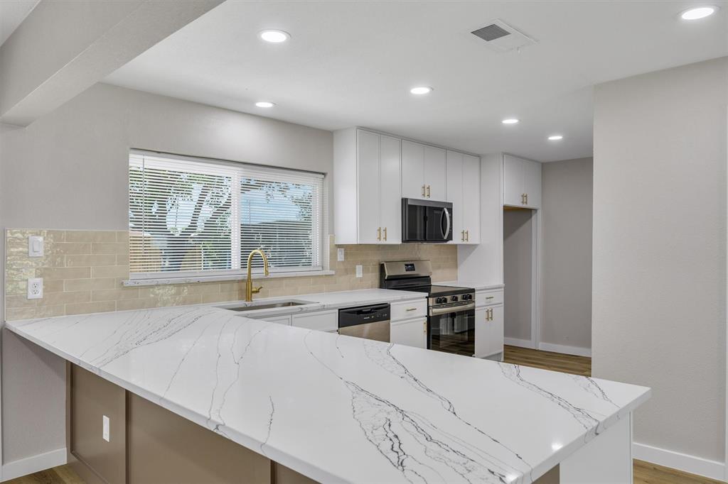 Kitchen featuring white shaker-style cabinetry, white countertops with grey veining, a subway tile backsplash, recessed lighting, and a gold-toned faucet