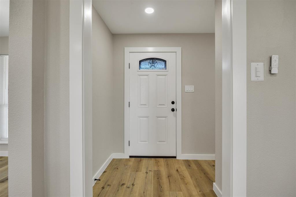 Entryway featuring wood-finish flooring, a white paneled front door with a decorative arched window insert, and recessed ceiling lighting
