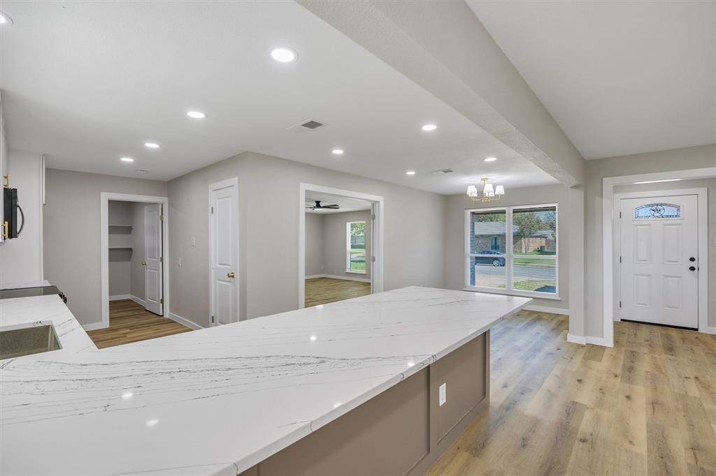 Kitchen featuring a large island with a stone-finish countertop, wood-finish flooring, recessed lighting, and multiple windows