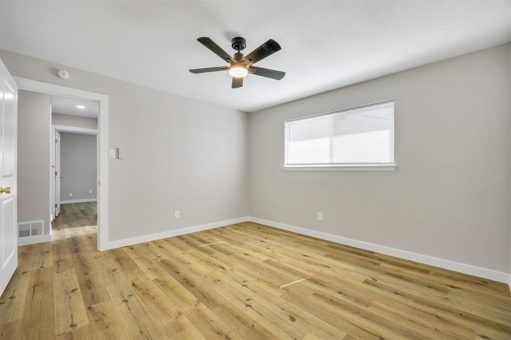 Neutral interior room featuring wood-finish flooring, a matte black ceiling fan with integrated lighting, and a horizontal sliding window