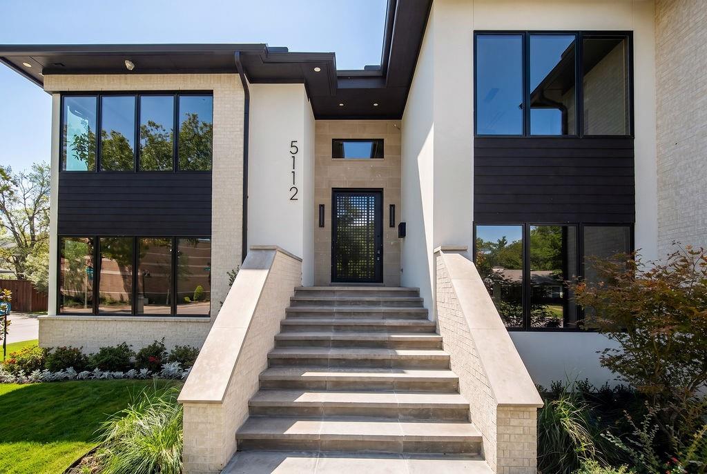 Walk up the stone steps framed by clean black window trim and architectural sconces, creating a warm and impressive entrance for friends and family