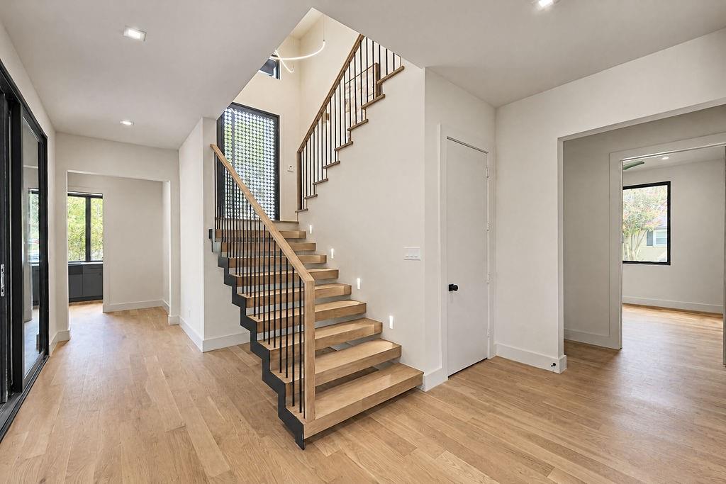 Step inside to a light-filled entry where rich hardwood floors and an open-riser floating staircase set an inviting, airy mood from the moment you cross the threshold