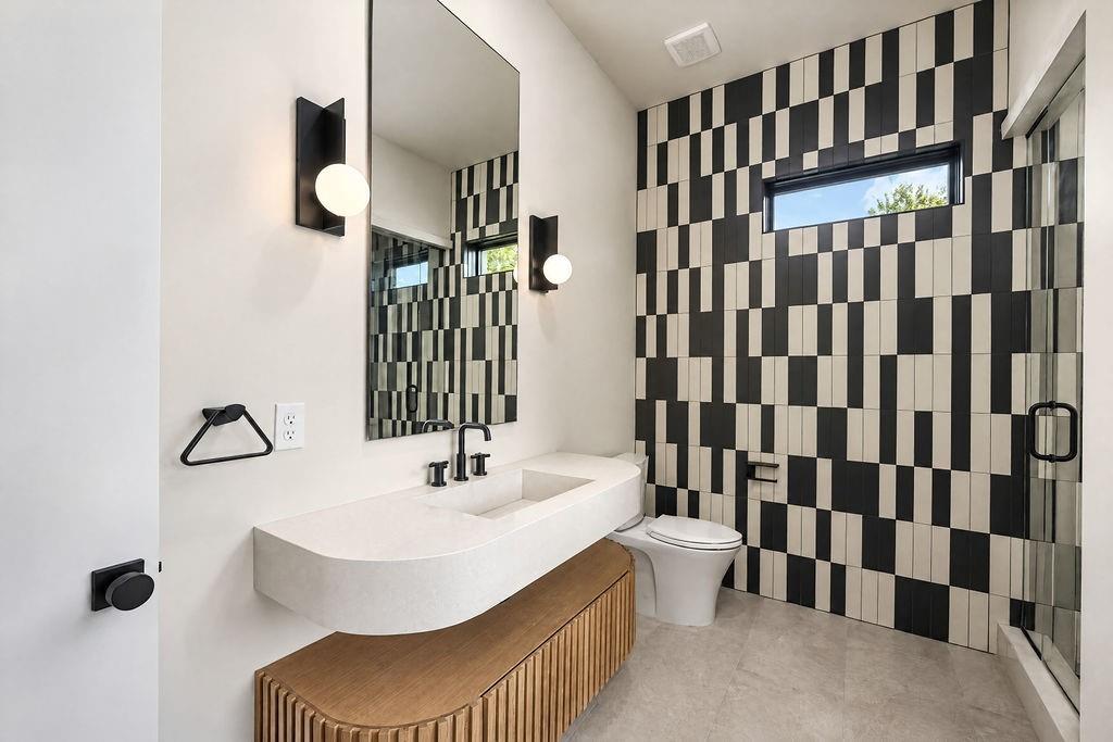 Experience bold modern personality with graphic black-and-white tile, a sculptural sink, and sleek black fixtures