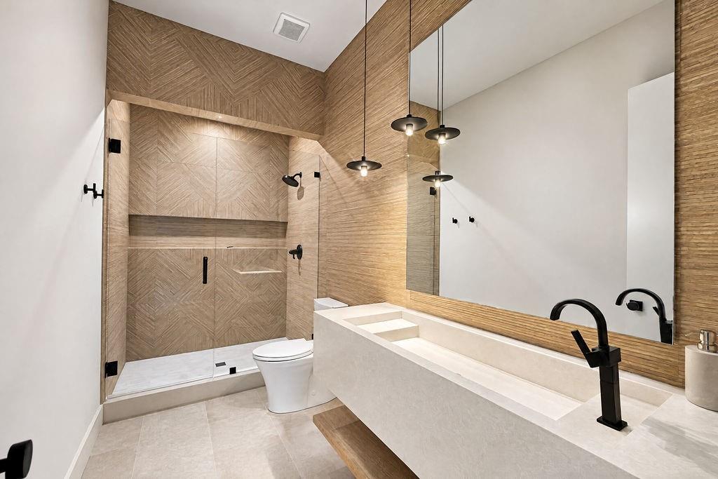 Wind down in a bathroom featuring a glass-enclosed shower, single vanity, and textured tile accents