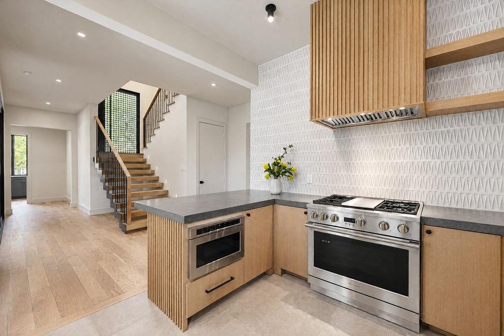 Savor simple weeknight cooking over the gas range, framed by custom wood cabinetry and stunning backsplash tile