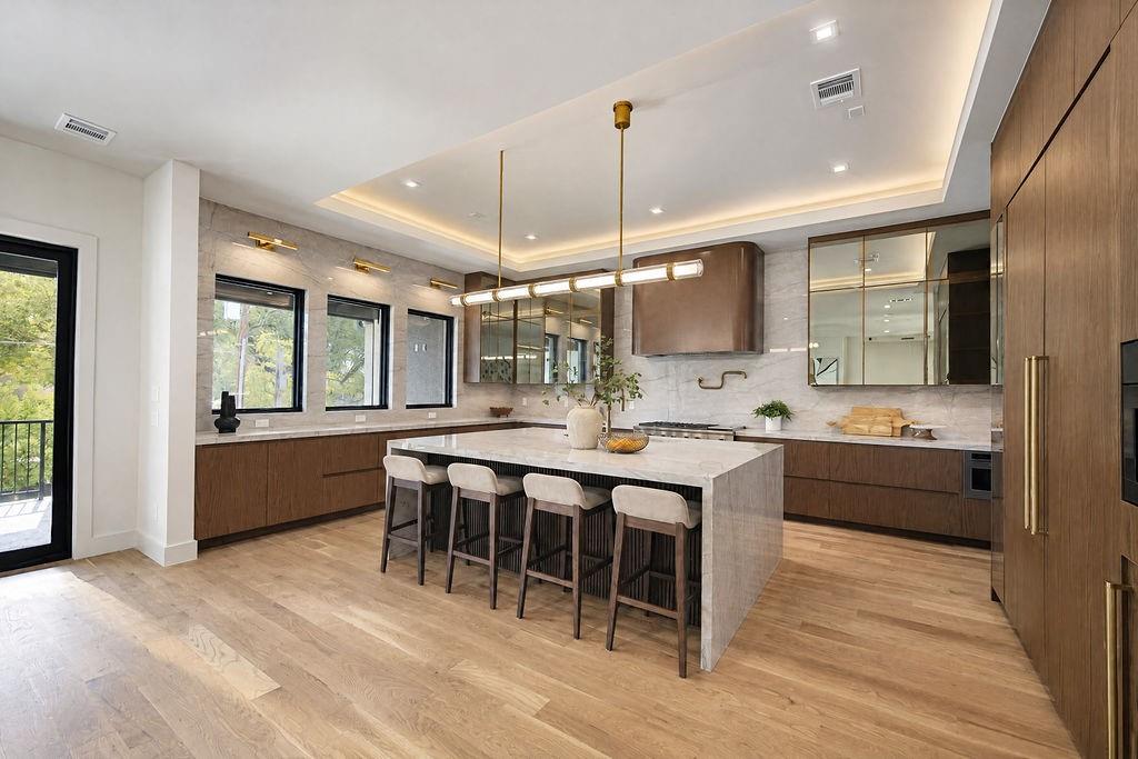 Gather around the quartzite island for breakfast while admiring custom walnut Florense cabinetry and the sculptural Visual Comfort fixture