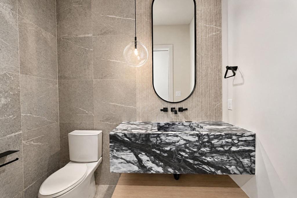 Treat guests to a memorable powder room experience featuring a floating vanity carved from dramatically veined stone and a hanging statement pendant