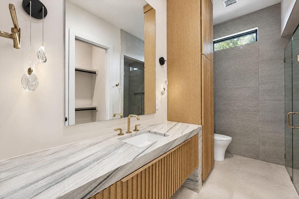 Refresh after a long day in a custom bath featuring a wide vanity, wood cabinetry, and custom lighting