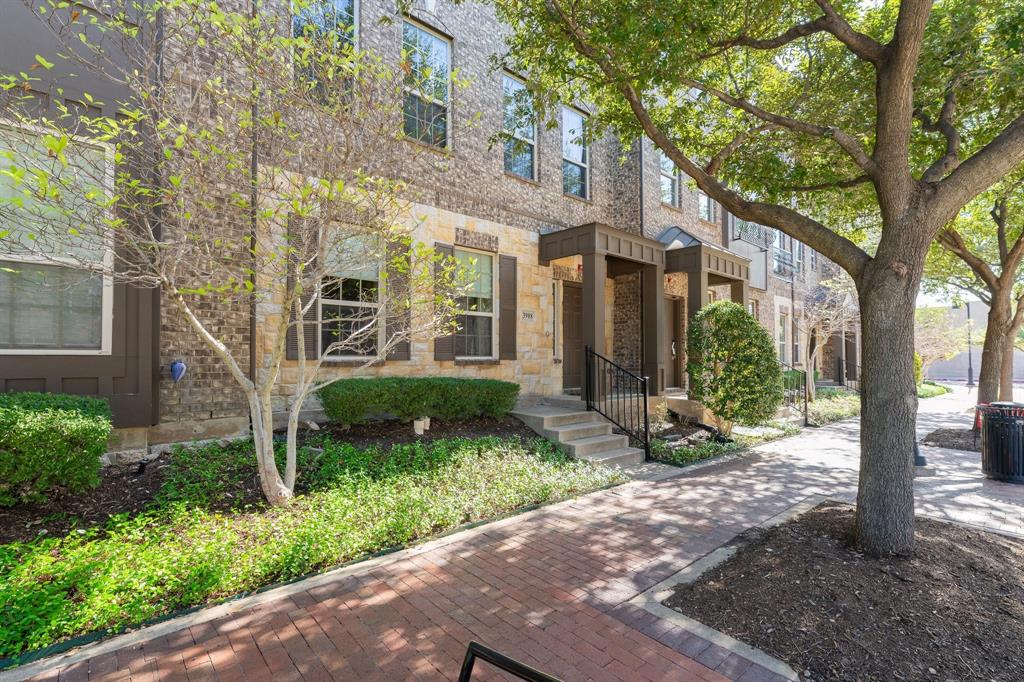 Multi-story exterior featuring a brick and stone facade, dark-toned shutters, covered entryway, and red brick pedestrian walkway
